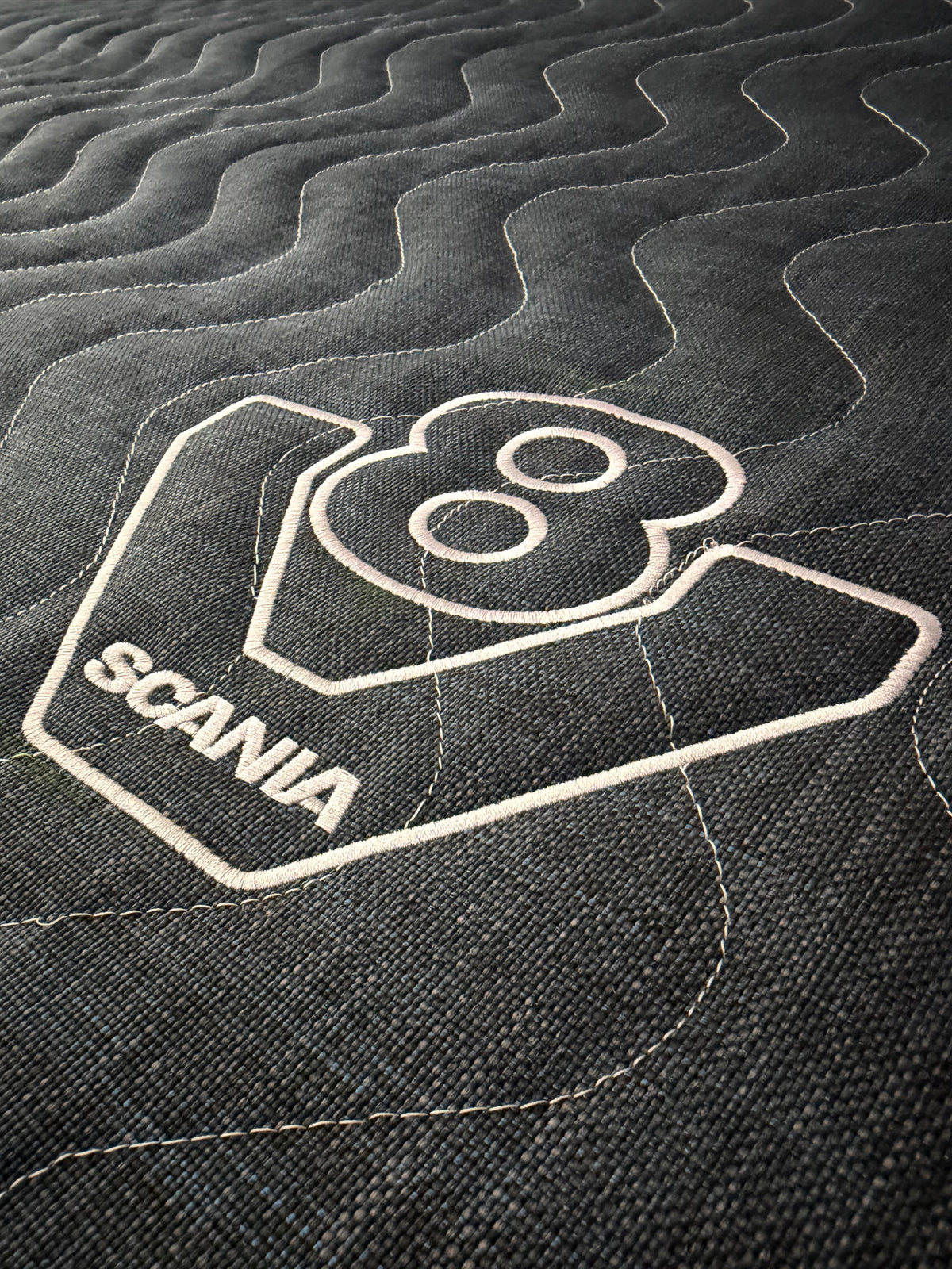Close-up showing the quilted fabric and Scania V8 branding